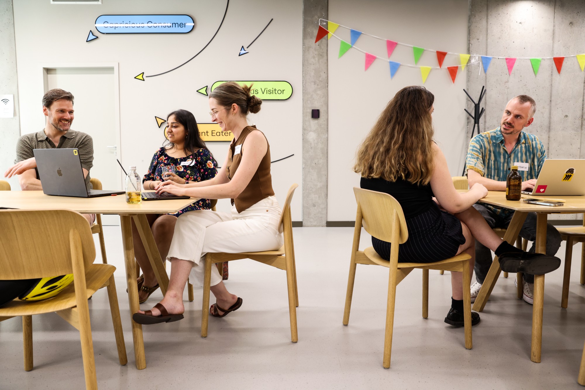 A Miro workshop: two tables of people talking over open laptops